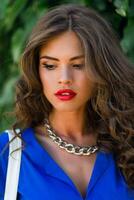 Close up lifestyle portrait of stunning brunette woman in  summer  casual outfit. Beautiful lady posing in the green summer park  lawn background . photo