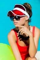 Sexy tanned    woman in red swimsuit having fun and enjoying  summer in amazing big swimming pool.  Stylish transparent cap. Beach party. photo