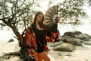Elegant woman in stylish  kimono  with large fan and professional make up posing outdoor. photo