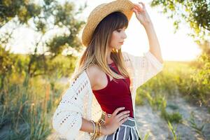 cerca arriba verano foto de bonito mujer en Paja sombrero posponer en el playa a puesta de sol ligero.