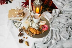 Still life with delicious Christmas gingerbread and cookies  breakfast on a tray in bed , donuts and croissants , cup of cacao or latte with cinnamon, ginger biscuits figure, Christmas candles. photo