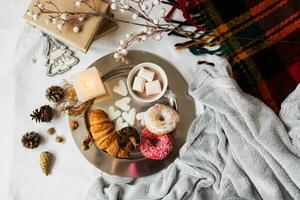 Still life with delicious Christmas gingerbread and cookies  breakfast on a tray in bed , donuts and croissants , cup of cacao or latte with cinnamon, ginger biscuits figure, Christmas candles. photo