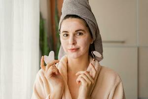 Skin care. Woman brushing clay mud mask to her face.  Posing on the modern livingroom.Cosmetic procedures. photo