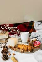Still life with delicious Christmas gingerbread and cookies  breakfast on a tray in bed , donuts and croissants , cup of cacao or latte with cinnamon, ginger biscuits figure, Christmas candles. photo