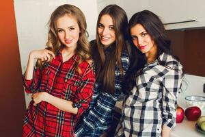 Close up indoor lifestyle portrait of three funny young friends have fun and pretending faces on the kitchen . Home party mood. Wearing plaid shirt. Warm soft photo. photo