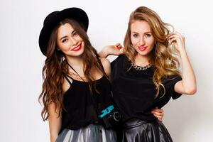 Two pretty stylish girls have fun and laughing. Best friends  in fall outfit posing in studio.Perfect wavy hairstyle. photo