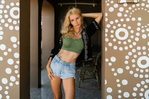 Summer fashion photo of seductive blond woman with perfcet figure  in  sexy top and jeanse posing outdoor. Wearing boho accesorises.