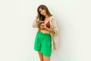 Summer portrait of stylish brunette woman  enjoing sweety lemonade and posing on white background. photo