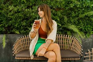 Cheerful  brunette woman  enjoing sweety lemonade and sitting in modern cafe. photo