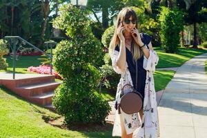 Amazing stylish  woman in blue playsuit  and white kimono enjoying vacation. She is smiling, showing signs. photo