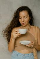 Close up portrait of beautiful brunette  woman with perfect wavy hairs enjoying cup of coffee in modern cafe. photo