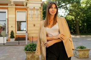 Fashion  brunette  elegant woman in sunglasses and casual jacket posing on the street in beautiful european city. photo