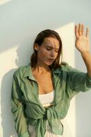 Fashionable woman  posing over wite background.  Casual outfit. Green linen blouse . white crop top and pants. photo