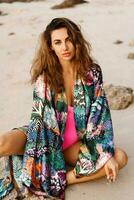 Close up portrait of romantic woman posing on the beach at sunset. Wearing stylish  trendy kimono with tropical print. Wavu hairs, natural make up . photo