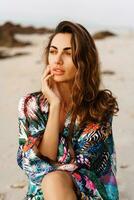 Close up portrait of romantic woman posing on the beach at sunset. Wearing stylish  trendy kimono with tropical print. Wavu hairs, natural make up . photo