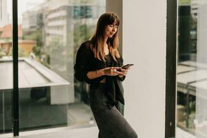 Stylish business woman in fashionable casual outfit  talking by mobyle phone  during work day in  modern business center. photo