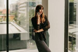 Stylish business woman in fashionable casual outfit  talking by mobyle phone  during work day in  modern business center. photo