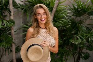 Close up portrait of  blond woman in stylish knitted  boho dress posing in luxury tropical resort.  Perfect smile. Red lips. wavy hairs . Vacation  mood. photo