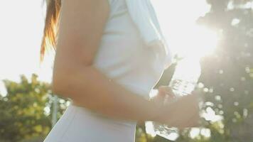 Young woman athlete takes a break, drinking water, out on a run on a hot day. video