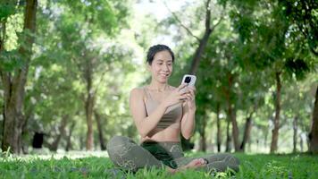 Asian woman playing with mobile phone in park video