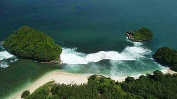View of Tanjung Turtle Mas, with big waves and two small islands covered with tropical plants video