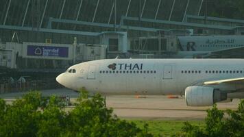 PHUKET, THAILAND NOVEMBER 26, 2016 - Tug and plane of THAI on the airfield at Phuket airport. Airplane towing. Side view, passenger huge jet on the taxiway video