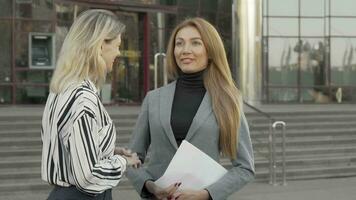 dos mujer de negocios sellando el acuerdo con apretón de manos en frente de oficina edificio video