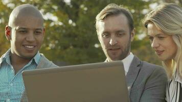 Sliding shot of three business colleagues using laptop at the park video