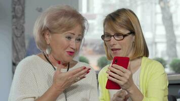 Mature woman showing something on her smart phone to her senior mother video