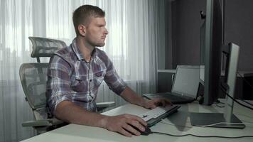 Beau il Bureau ouvrier en utilisant deux des ordinateurs travail sur une projet video