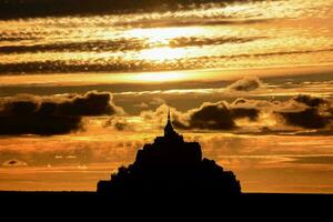 the sun sets behind the silhouette of a castle photo