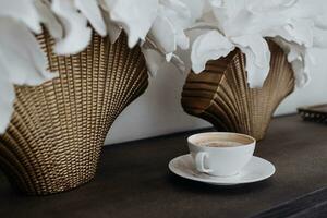 un de cerca de blanco porcelana café taza en un de madera mesa en a hogar. moderno interior diseño. capuchino con chocolate en el mesa. caliente café bebida concepto. foto