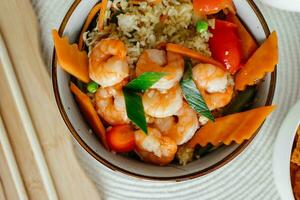 Quick and healthy Asian meal made of fried rice, fresh shrimps and vegetables in a bowl on the table. Top view, directly above shot with space for text. High quality photo