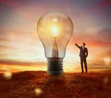 Businessman indicates a big light bulb as idea, resolution and creativity concept photo