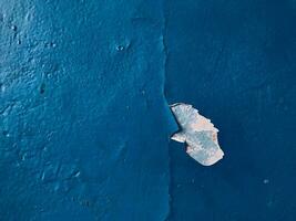 Blue paint on old concrete wall with cracks as background texture photo