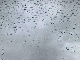 Drops of water on a transparent glass on background of a gray sky photo