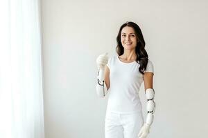 A Caucasian woman with a disability in a white T-shirt with prostheses instead of hands poses on a white background. Woman looking at the camera and smiling. AI Generative photo