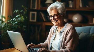 A beautiful pensioner woman looks into a laptop and smiles. A woman is sitting at home, studying something, chatting online or watching a video. AI Generative photo