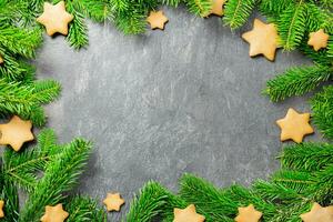 Christmas traditional gingerbread stars cookies with christmas tree branches on a dark stone background. Top view. Copy space. photo