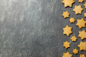 Christmas traditional gingerbread stars cookies on a dark stone background. Top view. Copy space. photo