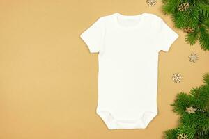 Christmas white baby girl or boy bodysuit mockup flat lay with xmas tree branches and snowflakes decoration on paper background. Design onesie template, print presentation mock up. Top view. photo