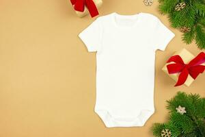 Christmas white baby girl or boy bodysuit mockup flat lay with gift boxes and xmas tree branches on paper background. Design onesie template, print presentation mock up. Top view. photo