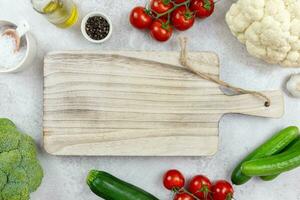 Assortment of healthy organic vegetables for balanced eating. Vegetarian whole food, plant based, clean eating concept with wooden cutting board mockup. Top view. Copy space. photo