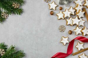 Christmas traditional German cookies, cinnamon stars with hazelnuts, decoration and tree branches on a light concrete background. Top view. Copy space. photo