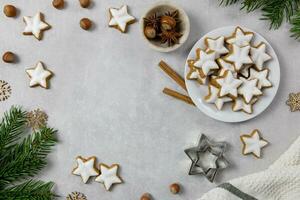 Christmas traditional German cookies, cinnamon stars with hazelnuts, decoration and tree branches on a light concrete background. Top view. Copy space. photo