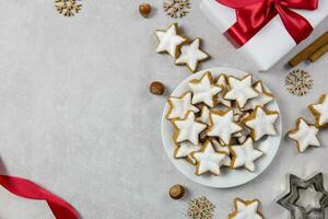 Christmas traditional German cookies, cinnamon stars with hazelnuts, decoration and tree branches on a light concrete background. Top view. Copy space. photo