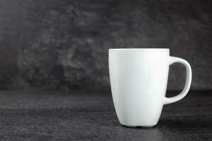 Classic white mug mockup on dark stone background. Side view. Copy space. photo