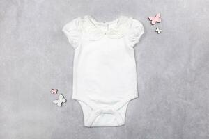 White baby girl bodysuit mockup flat lay on the gray concrete background. Design onesie template, print presentation mock up. Top view. photo