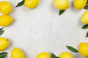 Fresh lemons with leaves on light gray concrete background. Vitamin C concept, immune defence. Top view. Copy space. photo