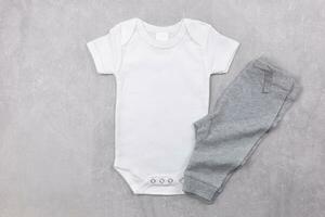 White baby girl or boy bodysuit mockup flat lay with gray panties on the concrete background. Design onesie template, print presentation mock up. Top view. photo